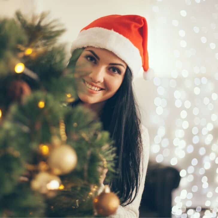 woman in santa hat decorating christmas tree