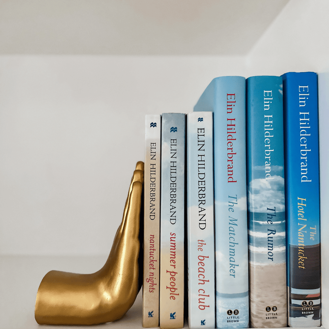 six elin hilderbrand books on bookshelf with bookend.