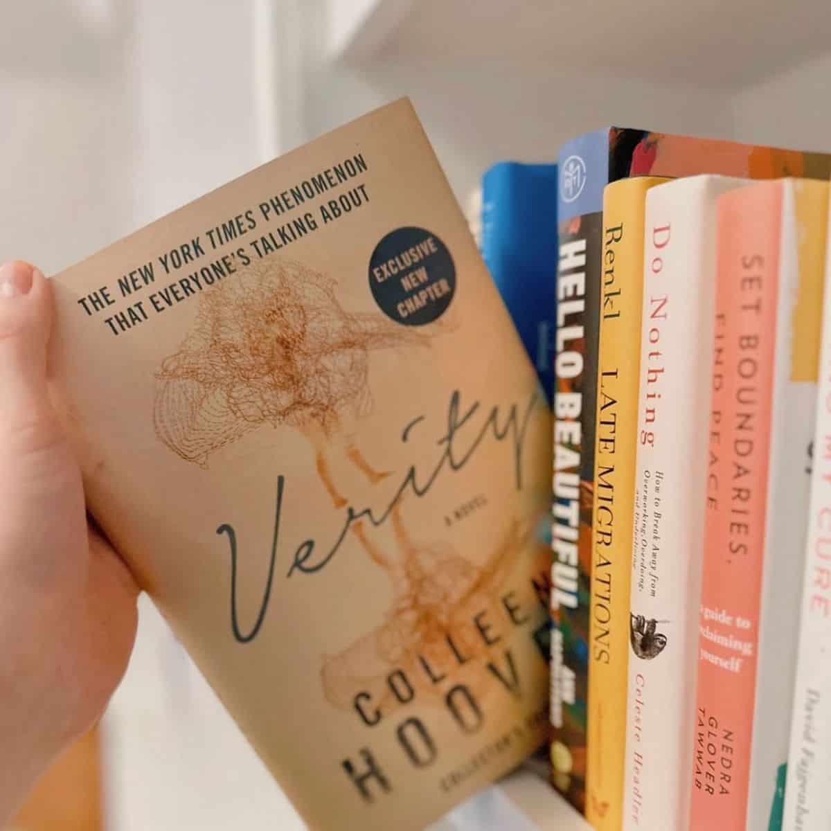 verity by colleen hoover being pulled from a bookshelf.