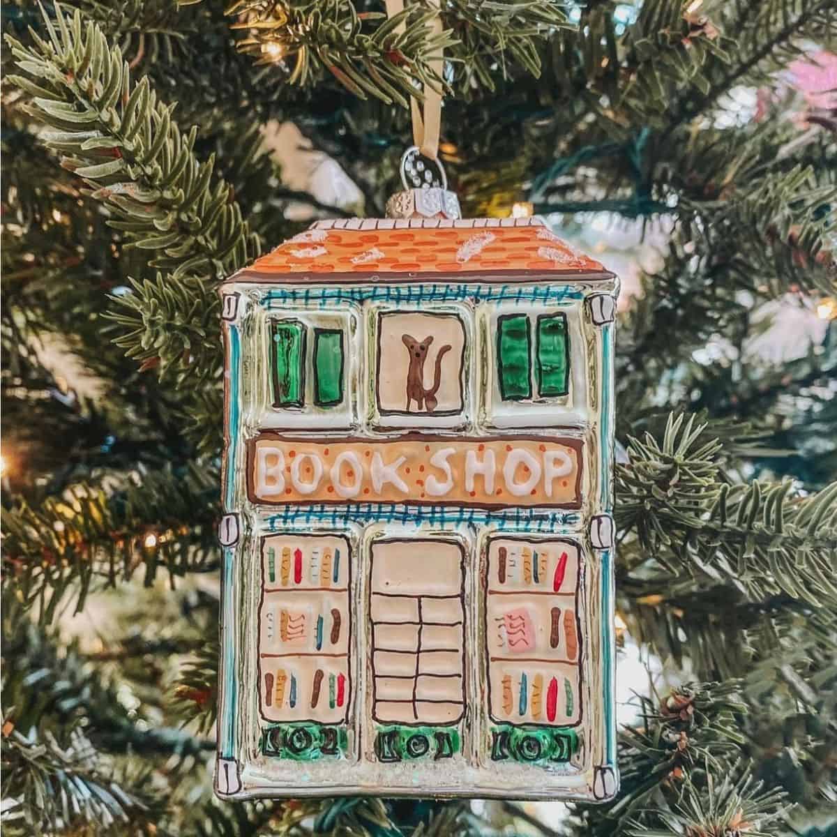 blown glass bookshop ornament in front of a tree.