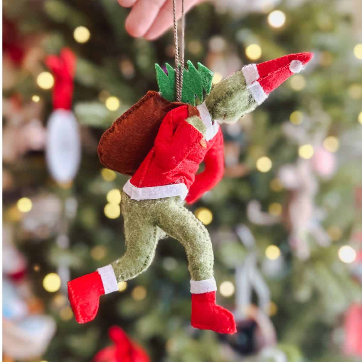 grinch ornament on christmas tree with heart ornaments.