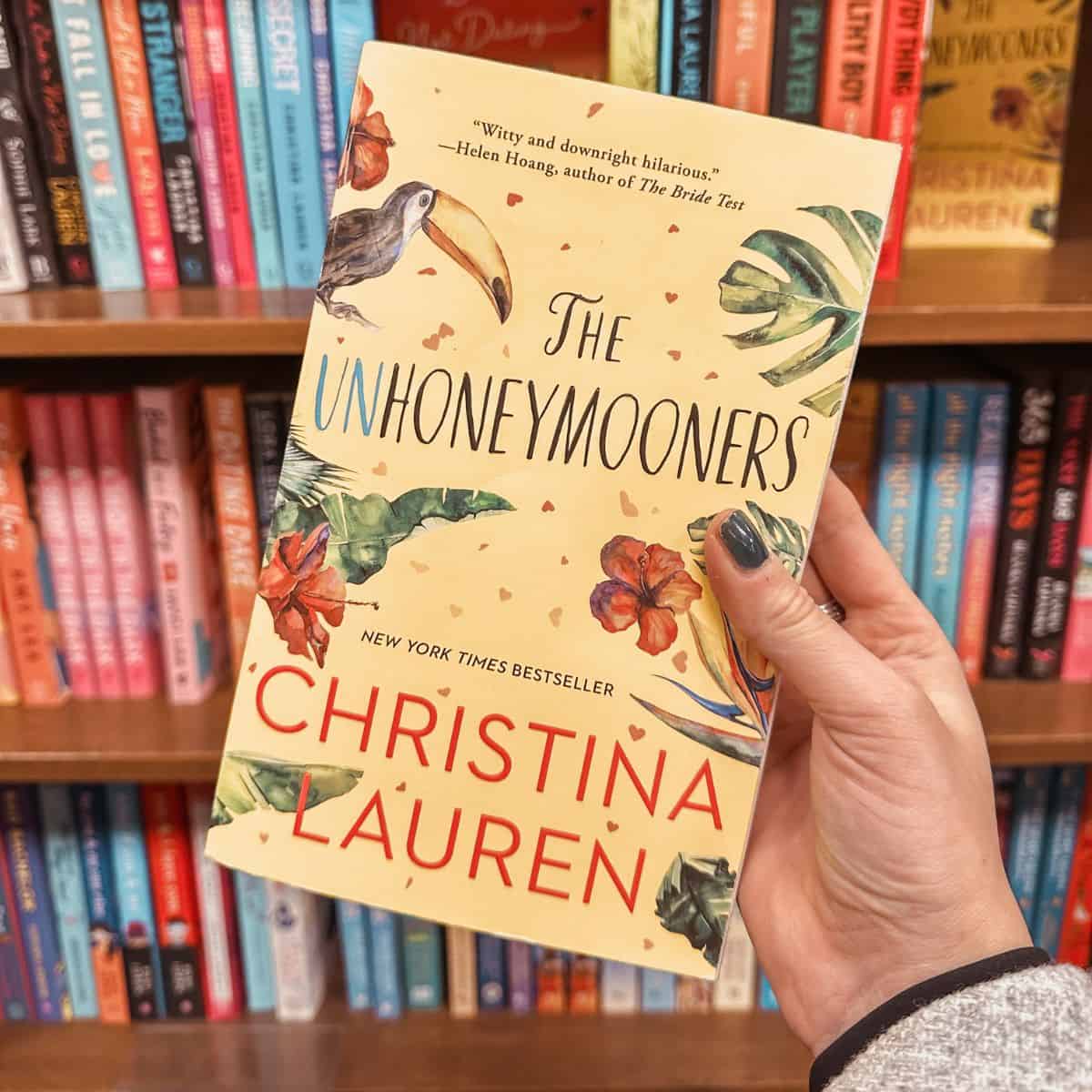the unhoneymooners by christina lauren in front on bookshelves.