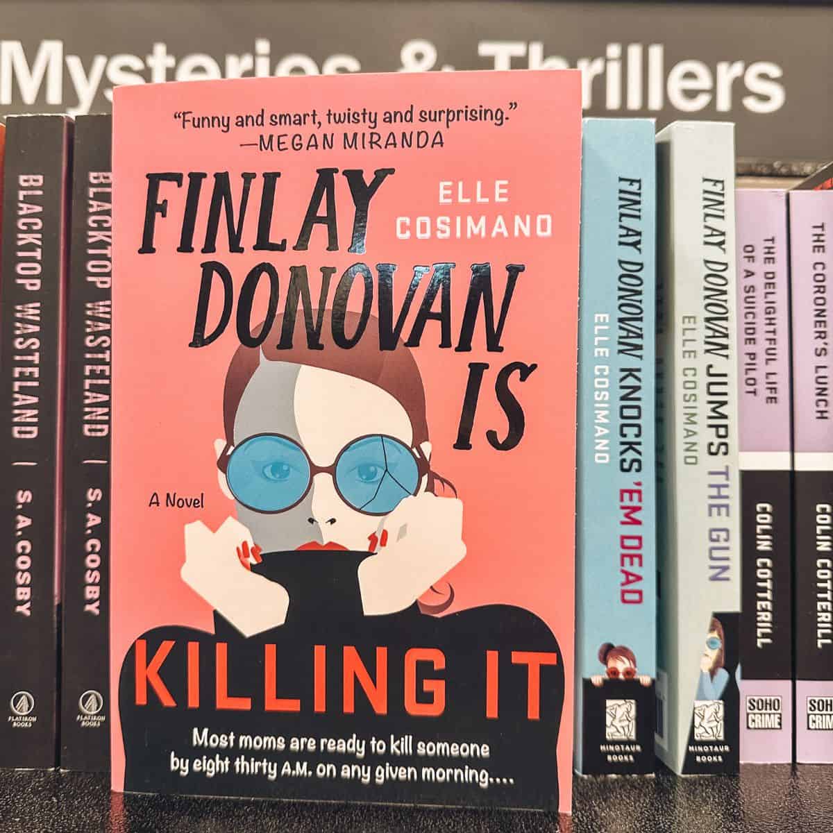 Finley Donovan is killing it books by Elle cosimano on a bookshelf.