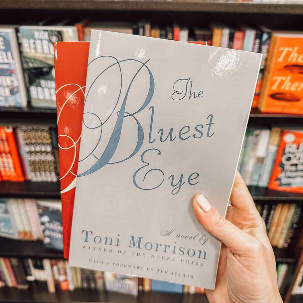 The Bluest Eye by Toni Morrison in front of a bookshelf.