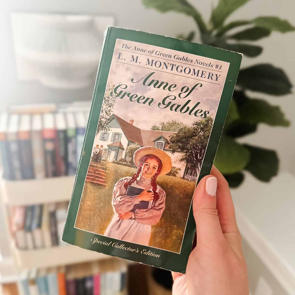 Anne of Green Gables by LM Montgomery held in front of a book cart.