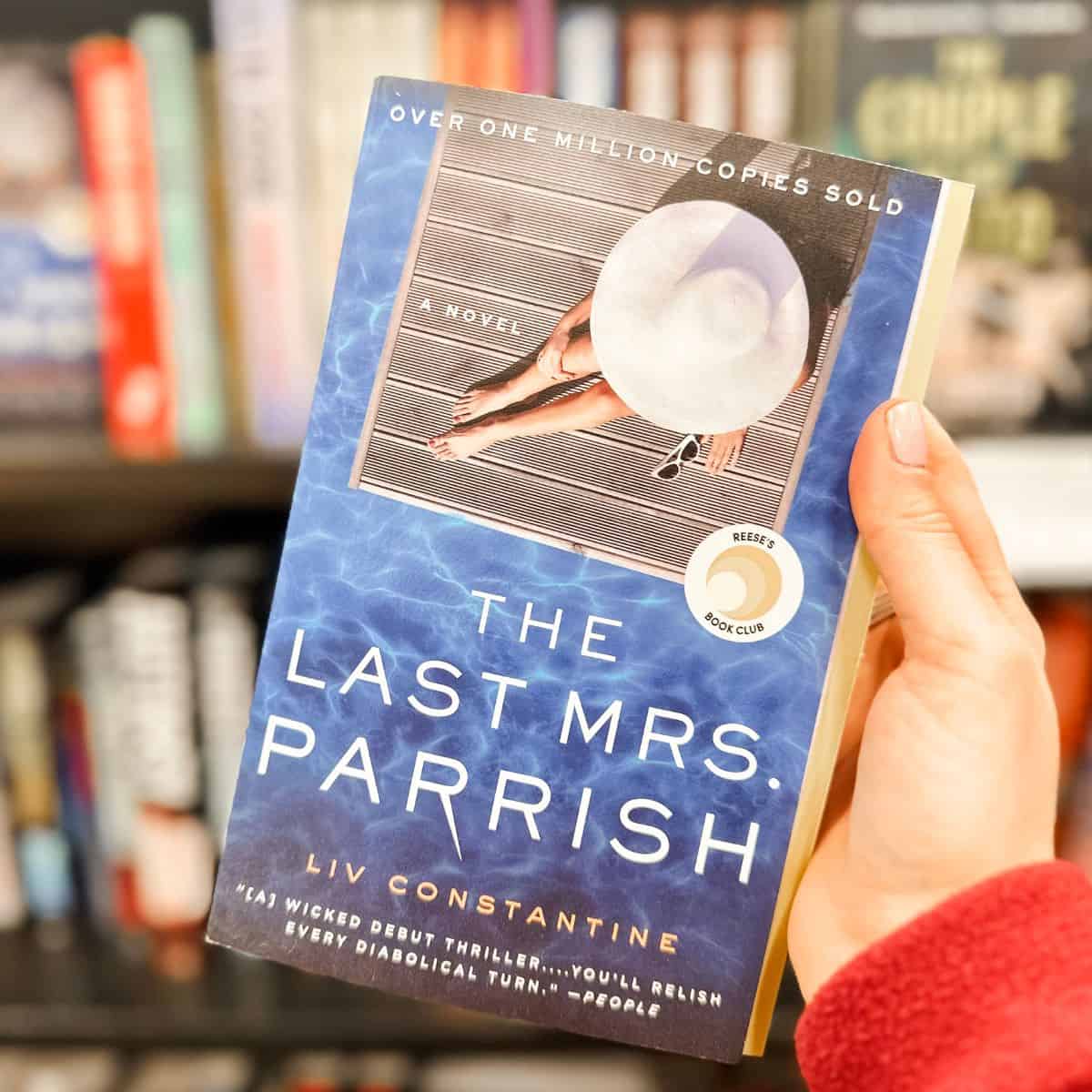 The last Mrs Parrish by liv Constantine held in front of a bookshelf.