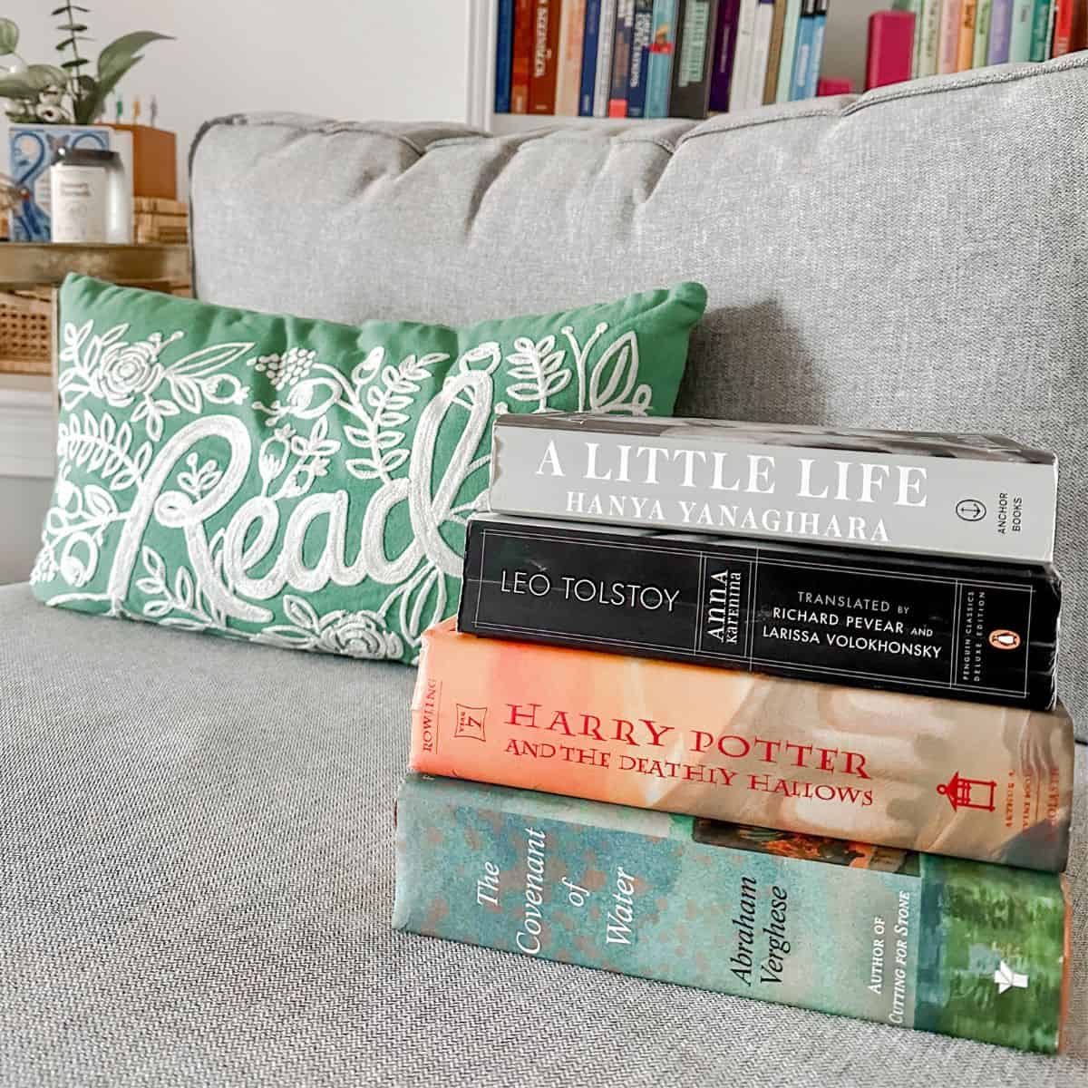Stack of big books in front of a pillow that says "read".