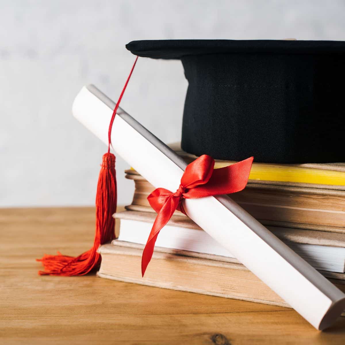 stack of books with graduation cap and diploma.